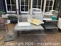 Group of bird cages and folded dog crates on patio table