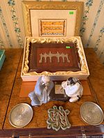 Full lot overview showing framed print, wood plaque in satin box, pair of porcelain figurines, green stone ornament, two Singapore coasters