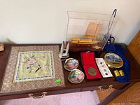 Group shot showing all items: embroidery, boat model, rope, tins, medallion, miniature monument, token card