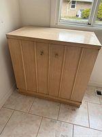 Front view of closed cabinet showing blonde finish and hardware