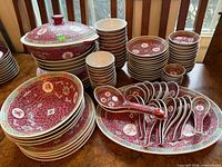 Group view of full dinnerware set with stacks of plates, bowls, platter, spoons, and covered tureen