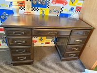 Front view of dark wood desk with eight drawers and metal pulls