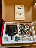 Open box showing drone, controller, charger, manual in foam tray