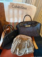 Group shot showing three Calvin Klein handbags and white dust cover