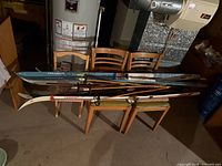 All four pairs of skis and two pole sets stacked on chairs