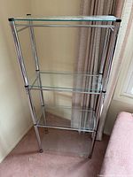 Full view of shelving unit with four glass shelves and metal frame