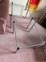Two square glass top metal tables on carpet
