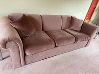 Three-seat pink sofa with pillows, rolled arms