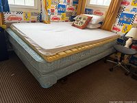 Full view of queen mattress on box spring with frame and toppers