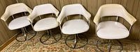 Four cream vinyl swivel chairs against wood panel wall