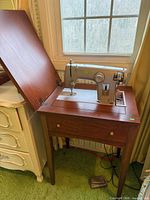 Sewing machine mounted in open wood cabinet, view of cabinet construction and machine placement
