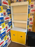Full view of white and yellow bookshelf cabinet