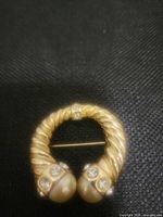 Front view showing twisted gold tone design, rhinestones and faux pearls