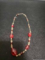 Full view of red glass bead necklace showing length and bead arrangement.