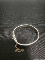 Closed view of silver-plated hinged bangle bracelet with safety chain