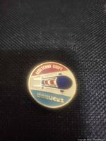 Front of circular enamel pin showing bobsled design and Cyrillic text