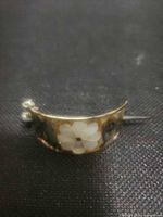 Front view of curved sterling hair pin showing mother of pearl flower and shell inlay