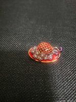 Front view showing red and purple enamel, rhinestone accents