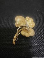 Front view of gold-tone floral brooch on dark background