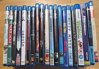 Row of approximately 23 Blu-ray cases showing assorted movie and TV titles