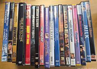 Row of approximately seventeen DVD cases showing spines with various movie and TV titles