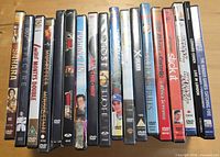 Row of approximately 19 DVD cases standing upright showing titles on spines
