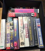 Top view of first row of VHS spines showing titles such as Home Alone, Cobra, The Sistine Chapel, Ghosts of the Bay, NFL Super Duper Football Follies, Dying Young and others