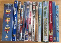 Row of 13 sealed kids and family movie cases showing spines