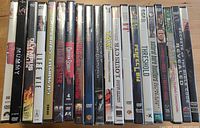 Row of nineteen factory-sealed DVD spines showing titles such as The Mummy, Taxi, Louis C.K., Threshold, Natural Born Killers