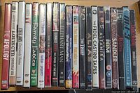 Front view of eighteen factory-sealed DVDs lined vertically, showing shrink-wrap and visible titles