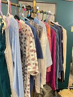 Assorted tops on rack, wide view showing variety of colours and sleeve lengths