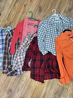 Seven assorted blouses laid out on wood floor