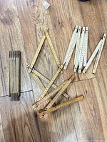 Three unfolded wooden folding rulers showing color variations and measurement markings