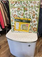 Hamper closed with packaged garment bag resting on lid