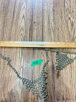 Necklace and hand chain bracelet laid out with ruler for scale