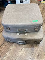 Stacked view of both beige hard shell suitcases closed