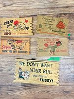 All five humorous plaques spread on wood floor