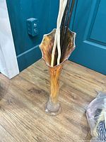 Tall iridescent glass vase with decorative sticks displayed inside
