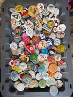 Full view of grey bin filled with assorted vintage pin-back buttons