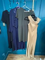 Four dresses hanging: black, blue, green, tan