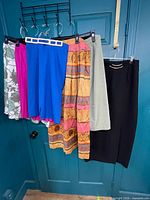 All six skirts hanging on hooks, showing colours and styles