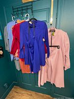 Six vintage women’s clothing sets on hangers, showing colours and styles