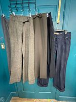 Five pairs of women’s pants hanging on door showing overall assortment