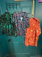 Three vintage women’s sets hanging on door showing various floral patterns