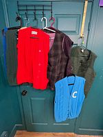 Seven vests hanging on door showing variety of colors and styles