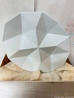 Front view of white faceted porcelain platter in box with tissue