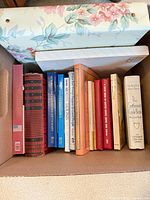 Box containing 13 books of assorted genres plus two photo albums on top