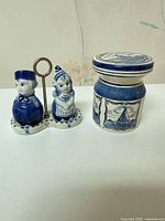 Full view of Delft boy and girl shakers on stand beside mustard jar