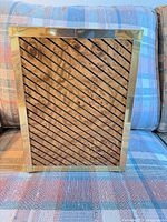 Front view of rectangular brass-tone framed box with diagonal-striped wood veneer panel