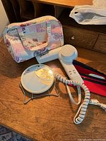 Hair dryer, mirror, floral toiletry bag and red pouch on table